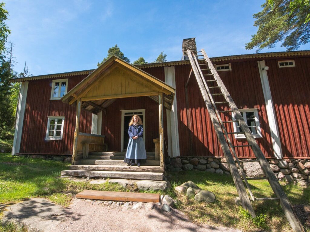 Seurasaaren ulkomuseon opas seisoo Kurssin talon kuistilla kansanpuvussa.